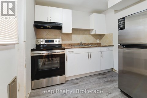 A kitchen with a stove top oven and white cabinets.