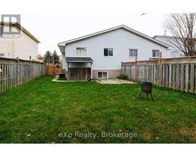 A backyard with a white house, a wooden fence, and a black chair.