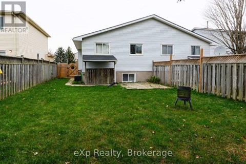 A backyard with a white house, a wooden fence, and a black chair.
