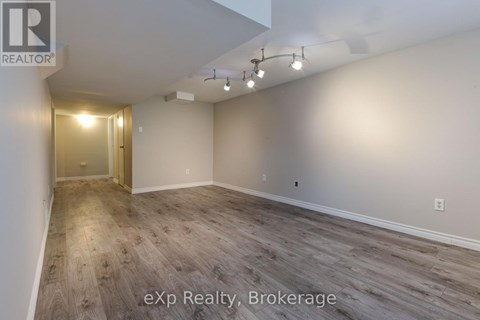 A room with wooden flooring and a doorway leading to another room.