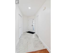 A hallway with marble flooring and white walls.