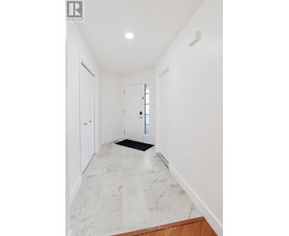 A hallway with marble flooring and white walls.