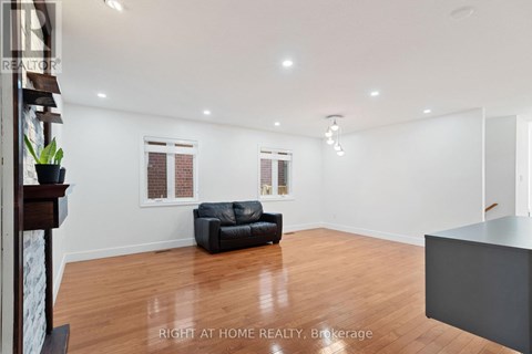 A spacious living room with a black leather sofa and wooden flooring.