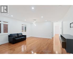 A spacious room with a black couch and wooden flooring.