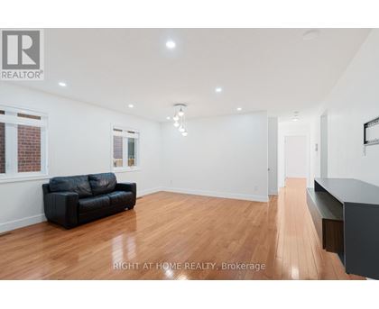 A spacious room with a black couch and wooden flooring.