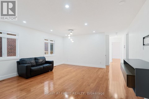 A spacious room with a black couch and wooden flooring.