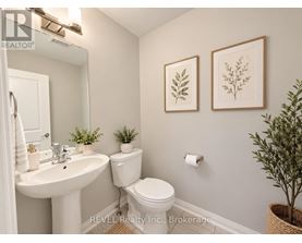 A bathroom with a white toilet, sink, and two framed leaves on the wall.