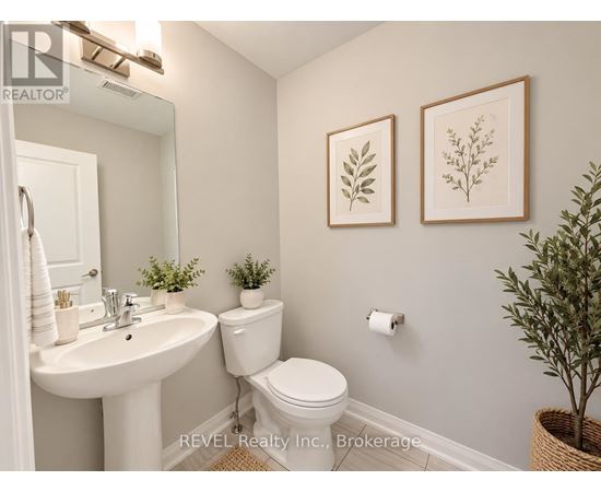A bathroom with a white toilet, sink, and two framed leaves on the wall.