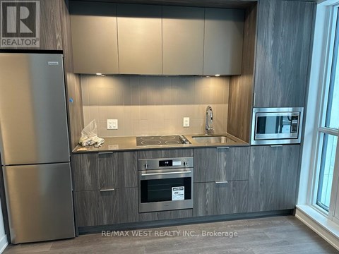 A modern kitchen with a stainless steel refrigerator and wooden cabinets.