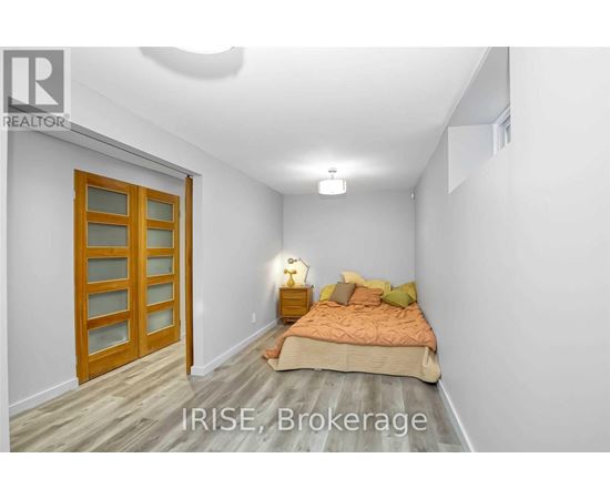 A bedroom with a bed, pillows, and a nightstand with a lamp.