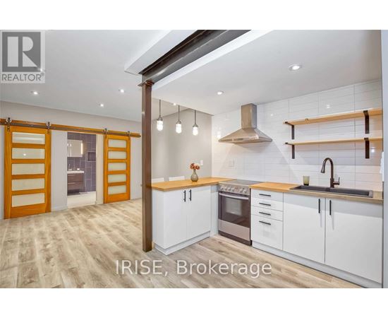 A modern kitchen with white cabinets and a wooden floor.