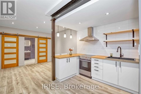 A modern kitchen with white cabinets and a wooden floor.