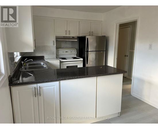 A kitchen with white cabinets and a black countertop.