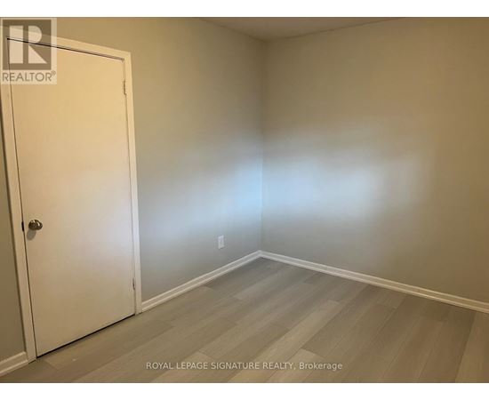 A room with a white door and wooden flooring.