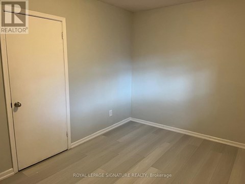 A room with a white door and wooden flooring.