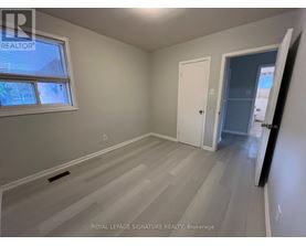 A room with a white door and a window with a view of a house.