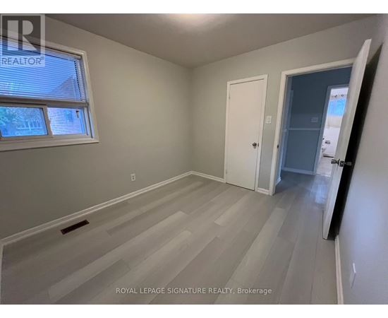 A room with a white door and a window with a view of a house.