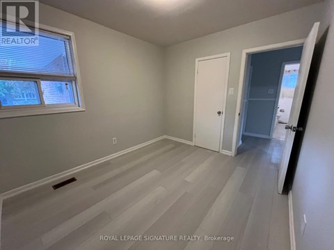 A room with a white door and a window with a view of a house.