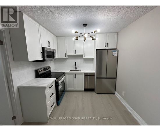 A kitchen with white cabinets and a stainless steel refrigerator.