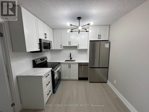 A kitchen with white cabinets and a stainless steel refrigerator.