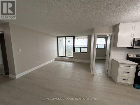 A spacious room with a kitchenette and a view of the outside through the sliding glass doors.