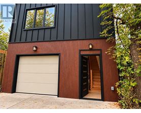 A modern house with a black and brown exterior and a white garage door.