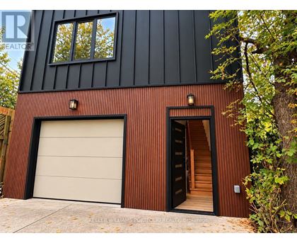 A modern house with a black and brown exterior and a white garage door.