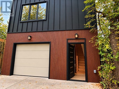 A modern house with a black and brown exterior and a white garage door.