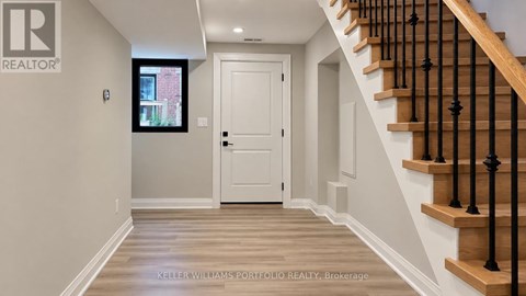 A hallway with a staircase and a door.
