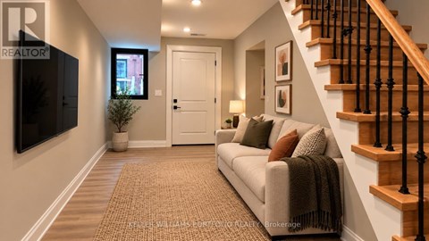 A living room with a couch, a television, and a staircase.