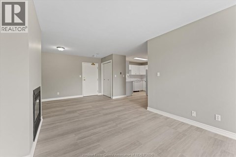A spacious room with a fireplace and wood flooring.
