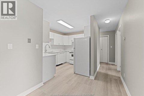 A kitchen with white appliances and cabinets in a real estate listing.