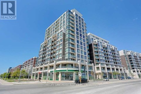 A large, modern apartment building with a glass facade and a green awning.