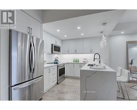 A modern kitchen with a refrigerator, microwave, and sink.