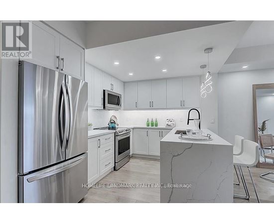 A modern kitchen with a refrigerator, microwave, and sink.