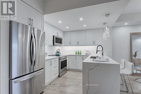 A modern kitchen with a refrigerator, microwave, and sink.