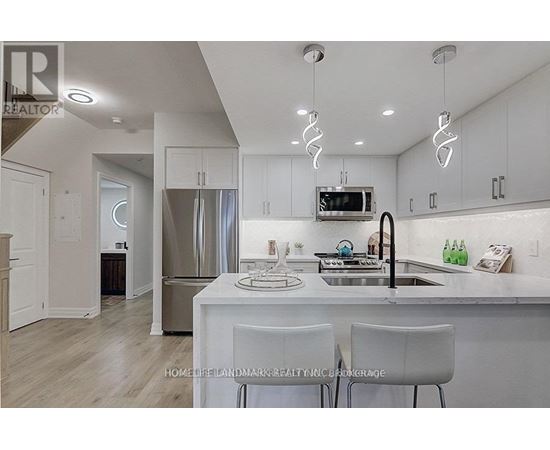 A modern kitchen with white cabinets and a stainless steel refrigerator.