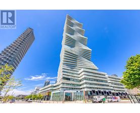 A tall, modern building with a unique design stands in the foreground with a clear blue sky above.