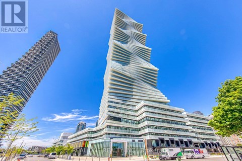 A tall, modern building with a unique design stands in the foreground with a clear blue sky above.