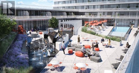 A group of people are sitting and standing on a patio with a pool.