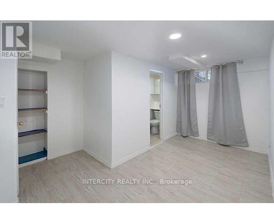 A white room with a grey curtain and a sign that says Intercity Realty Inc. Brokerage.