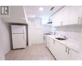 A kitchen with white cabinets and a white fridge.