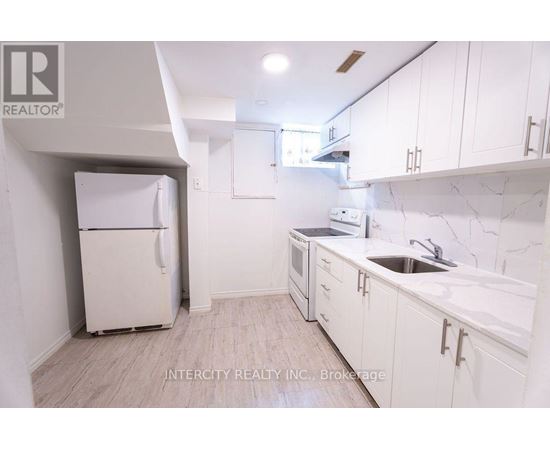 A kitchen with white cabinets and a white fridge.