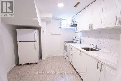 A kitchen with white cabinets and a white fridge.
