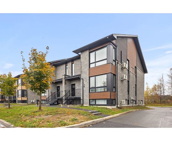 A modern two-story residential building with a mix of brick and wood paneling.