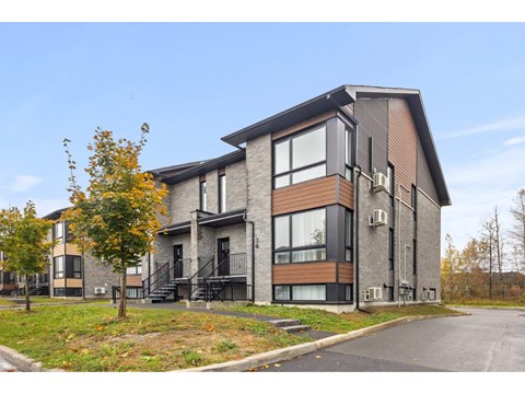 A modern two-story residential building with a mix of brick and wood paneling.