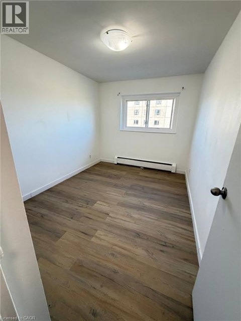 A room with wooden flooring and a window with blinds.
