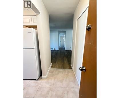 A hallway with a white fridge and a brown door.