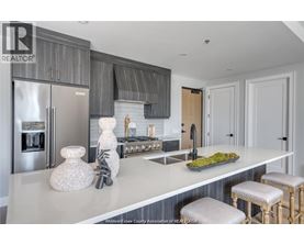 A kitchen with a white counter top and a stainless steel refrigerator.