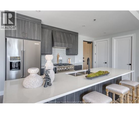 A kitchen with a white counter top and a stainless steel refrigerator.